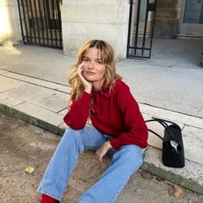 French woman wears a red sweater with red socks, loafers and jeans in Paris