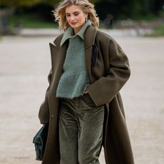 woman in olive green coat, corduroy pants, and sweater